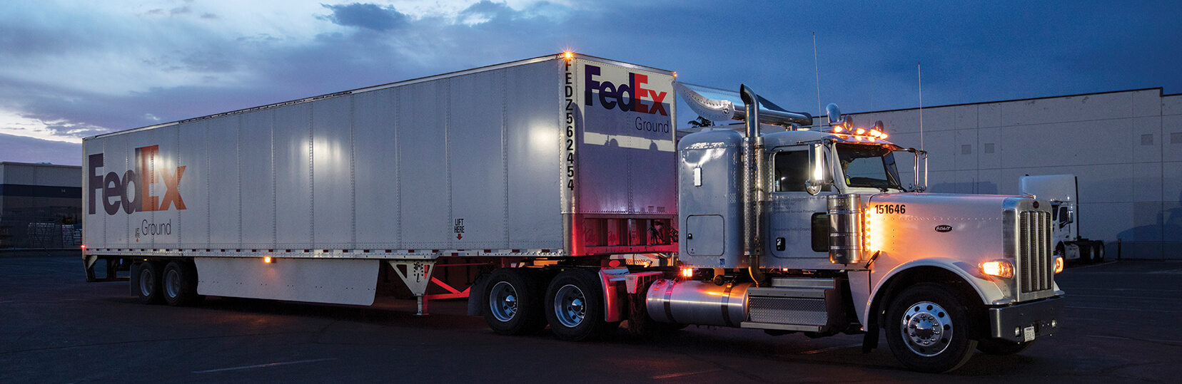 Freeport Peterbilt tractor pulling a FedEx Ground trailer out of the yard at dusk