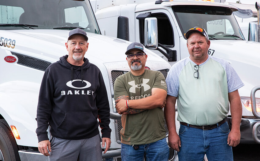 Three Freeport drivers standing in front of their trucks at the Sparks yard